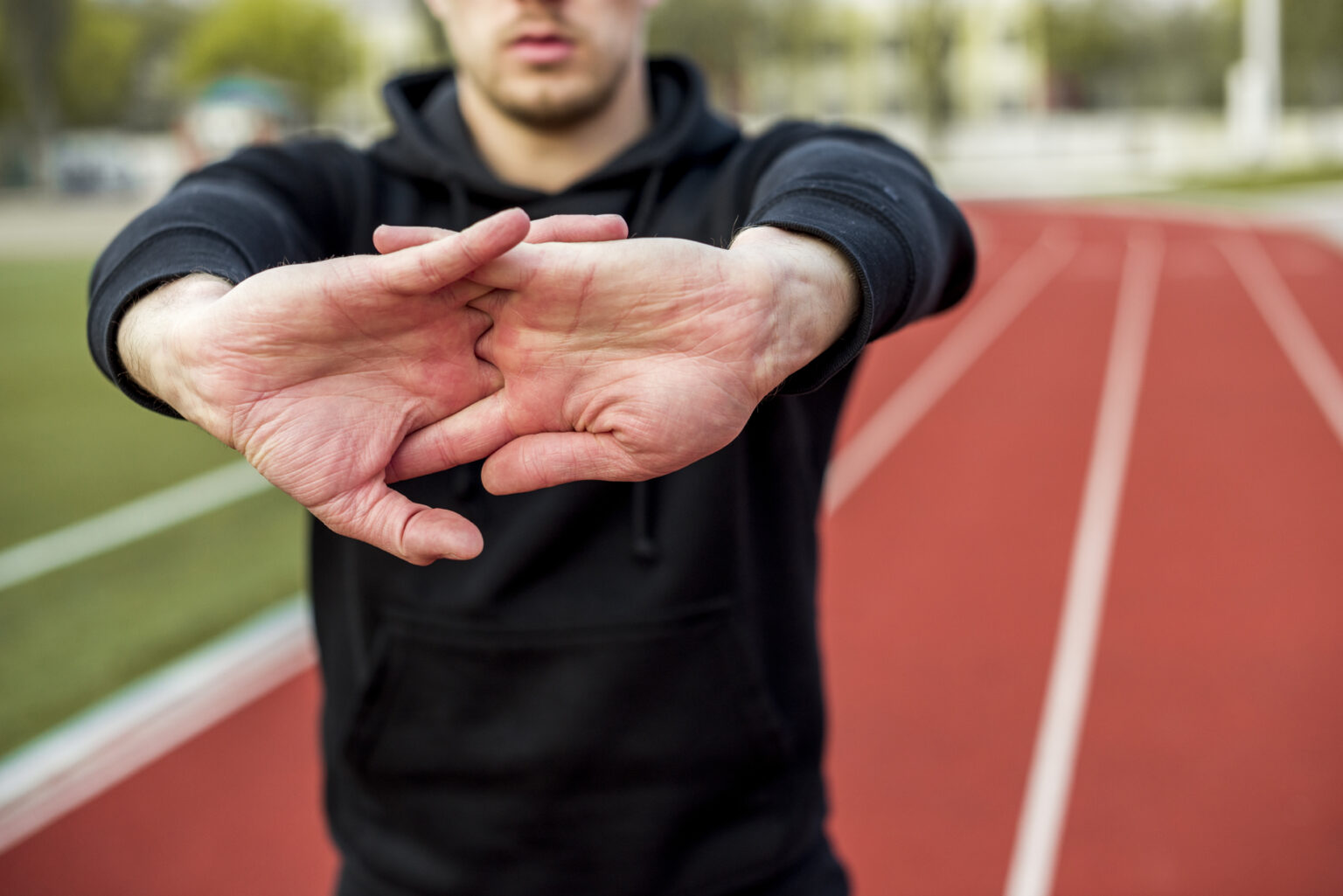 Direito para atletas: como garantir salários, luvas e benefícios corretamente? close up desportista masculina esticando as maos na pista de corrida